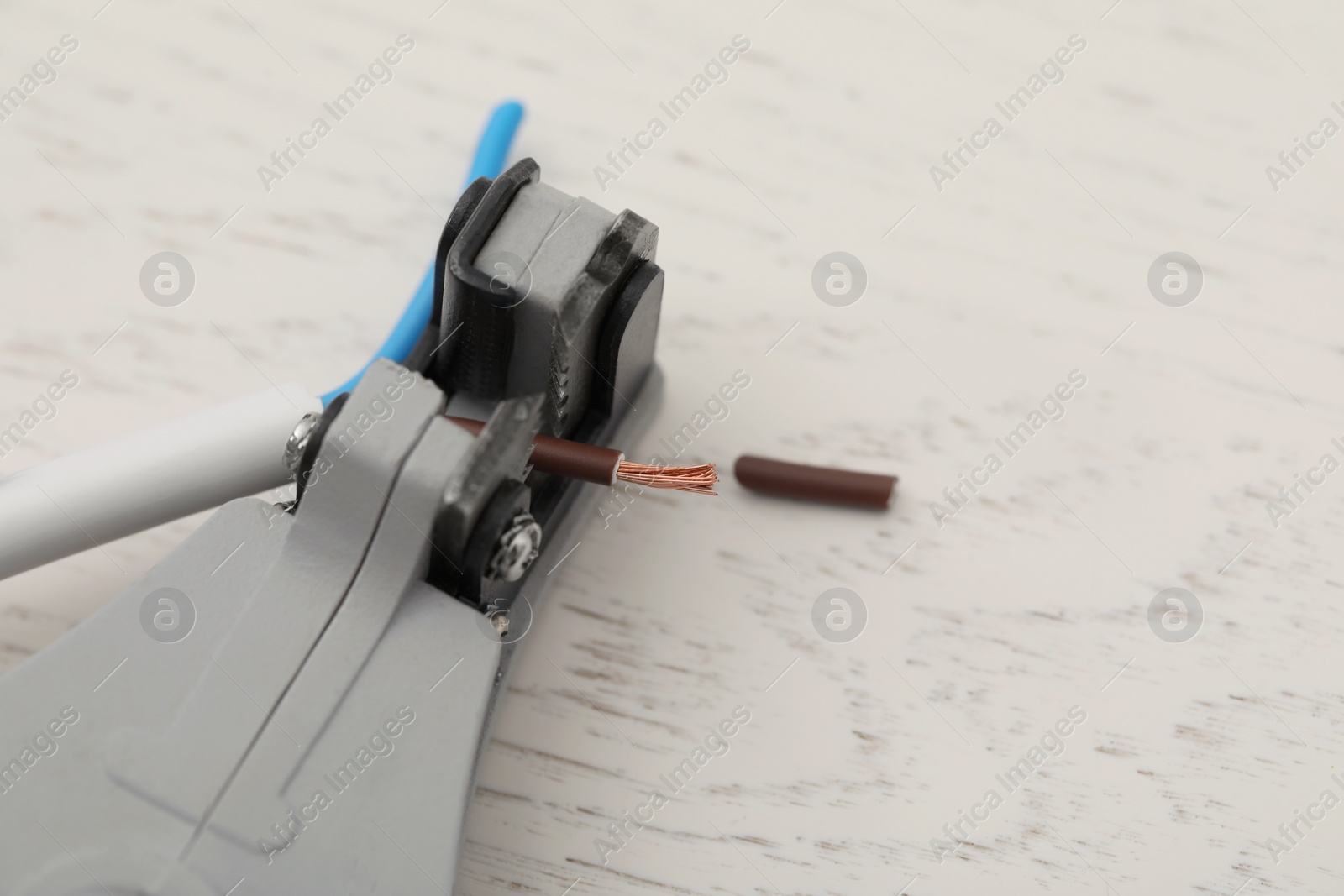 Photo of Cutters and stripped wire on white wooden table, closeup. Space for text