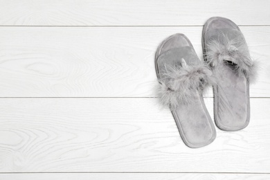 Pair of soft slippers on white wooden background, flat lay. Space for text