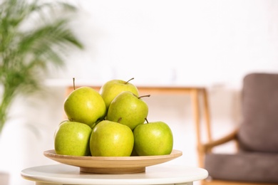 Plate with sweet green apples on table in living room, space for text