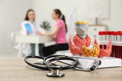 Photo of Endocrinologist examining patient at clinic, focus on stethoscope and model of thyroid gland