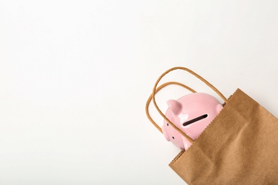 Flat lay composition with shopping bag and piggy bank on white background