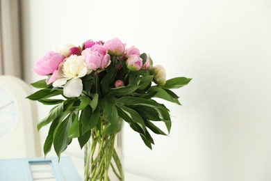 Photo of Vase with bouquet of beautiful peonies in room, space for text