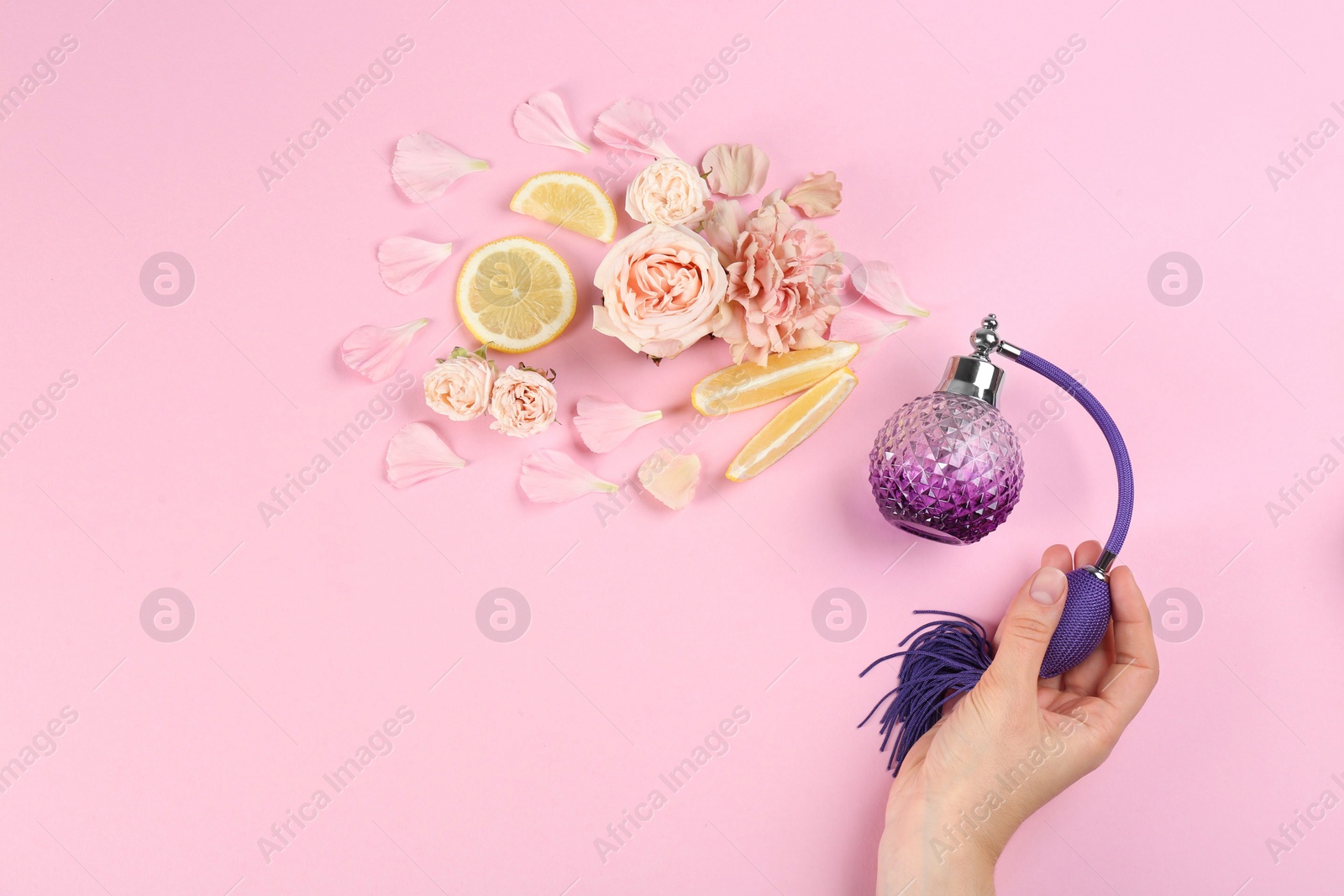 Photo of Woman with perfume. Fragrance composition, flowers and lemon on pink background,  top view