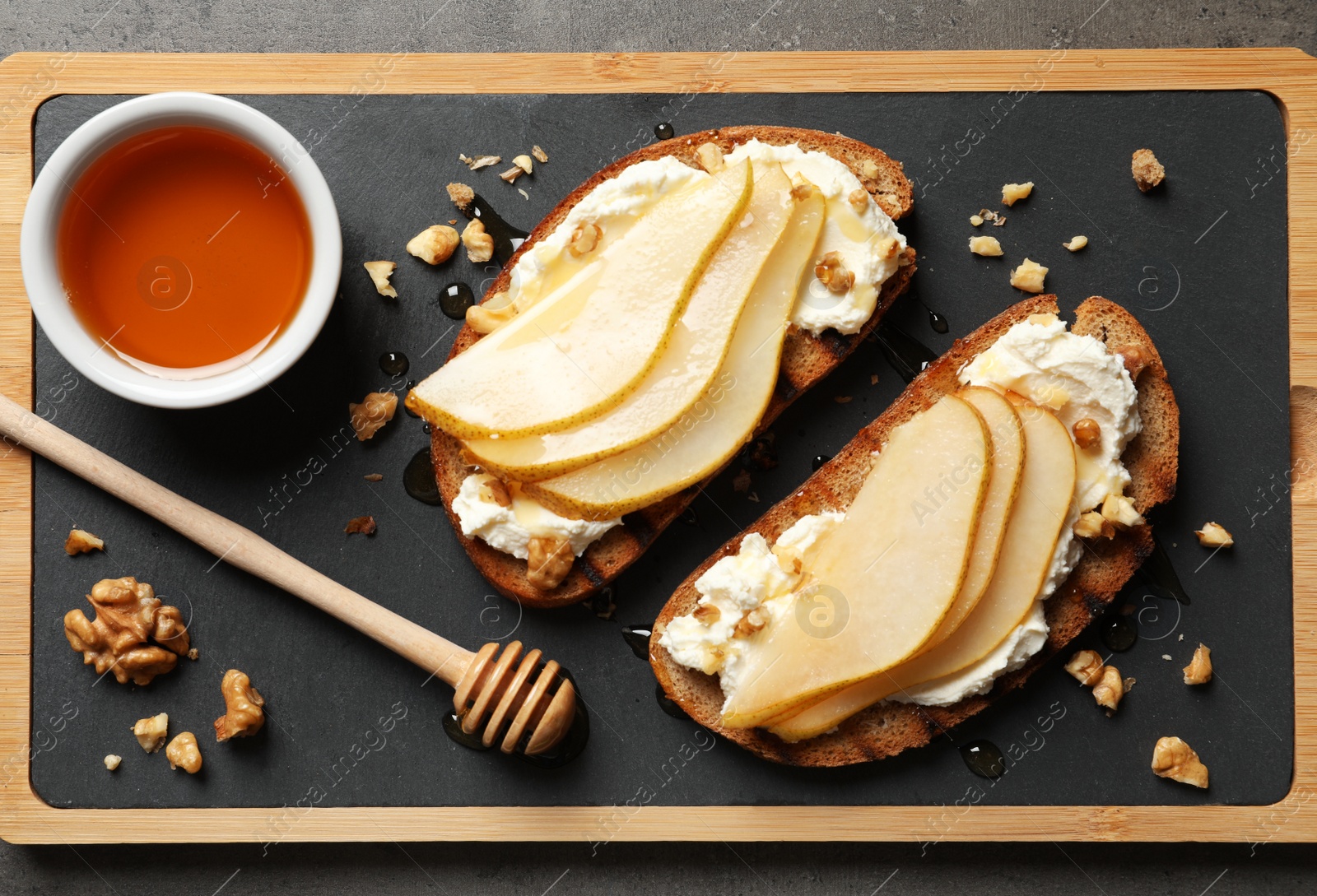 Photo of Toasted bread with tasty cream cheese and pear on board, flat lay