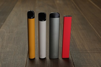 Photo of Many different electronic cigarettes on wooden table