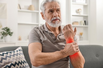 Image of Senior man suffering from pain in arm indoors