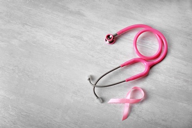 Pink ribbon with stethoscope on light background, space for text. Breast cancer concept