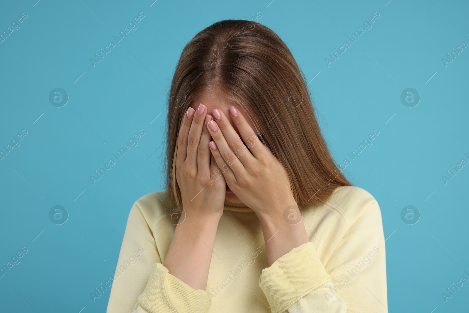 Photo of Resentful woman covering face with hands on light blue background