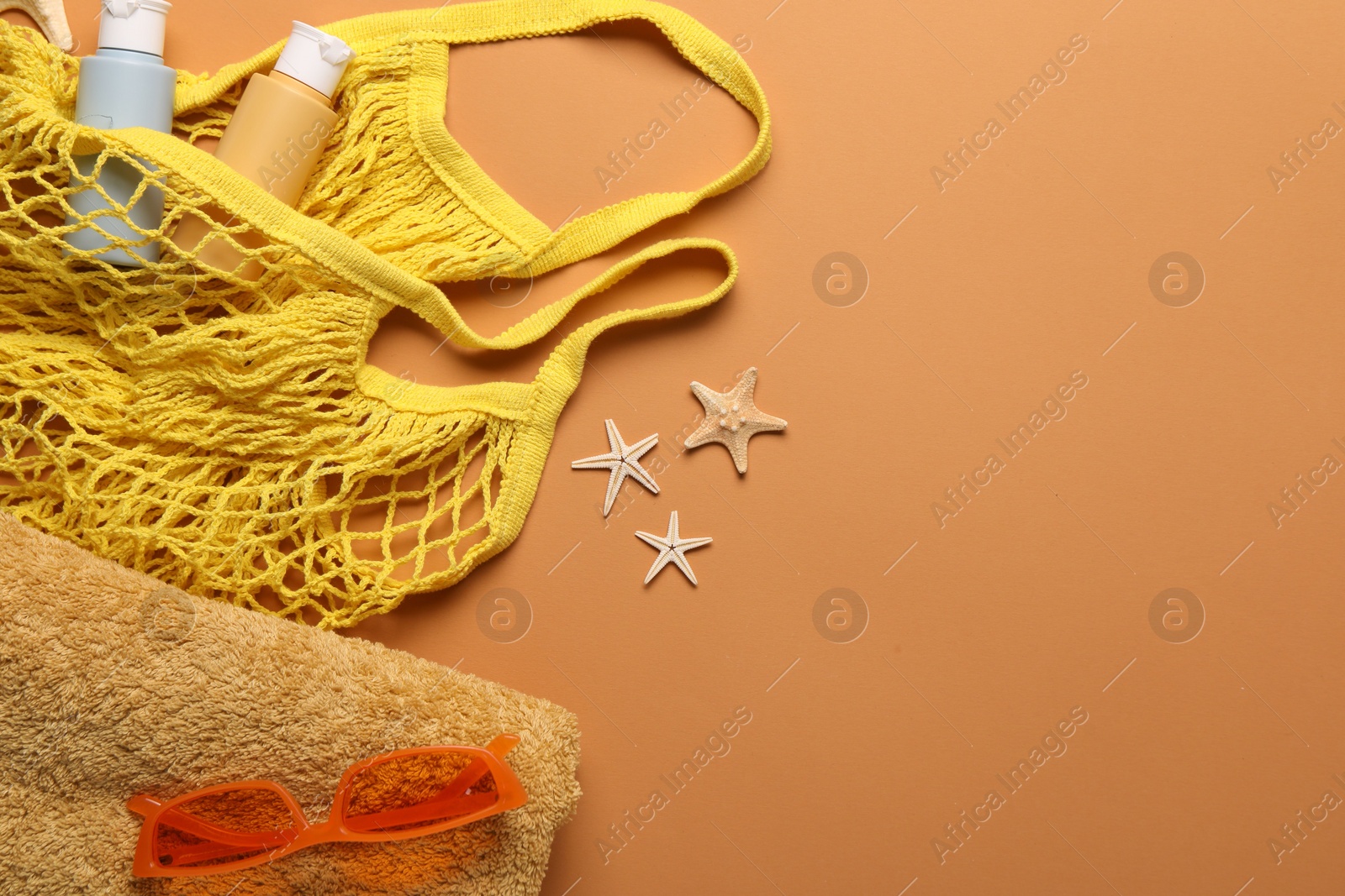 Photo of String bag and different beach accessories on pale orange background, top view. Space for text