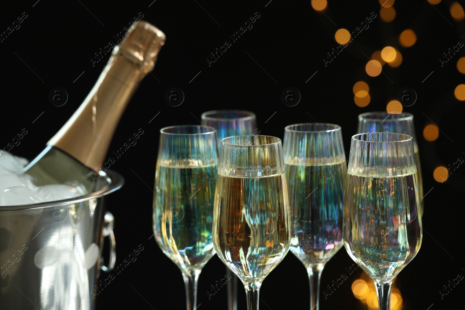 Photo of Glasses of champagne and ice bucket with bottle on black background