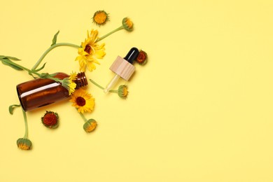 Bottle and pipette of essential oil near beautiful calendula flowers on yellow background, flat lay. Space for text