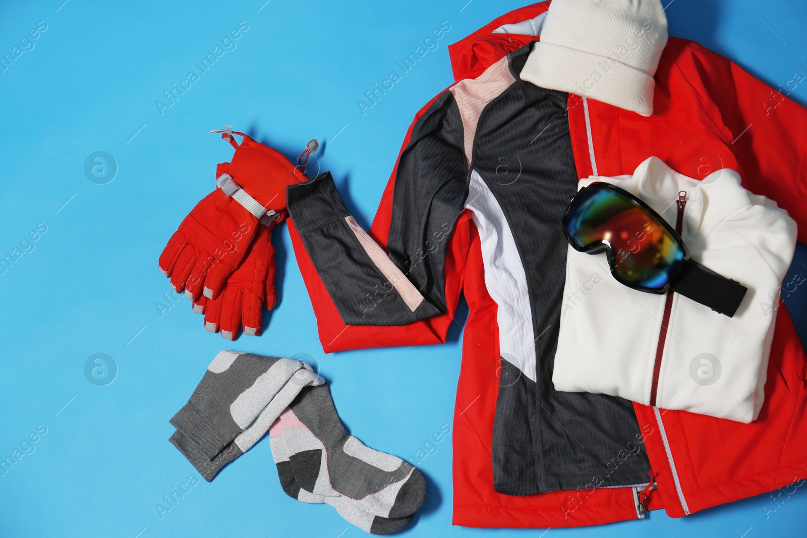 Photo of Stylish winter sport clothes on light blue background, flat lay