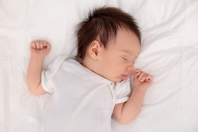 Cute newborn baby sleeping on bed, top view