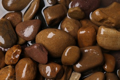 Photo of Beautiful pebbles in water as background, top view