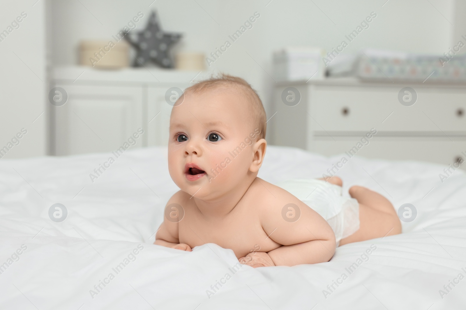 Photo of Cute baby lying on white bed at home