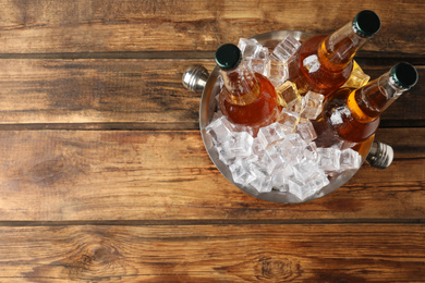 Photo of Metal bucket with beer and ice cubes on wooden background, top view. Space for text