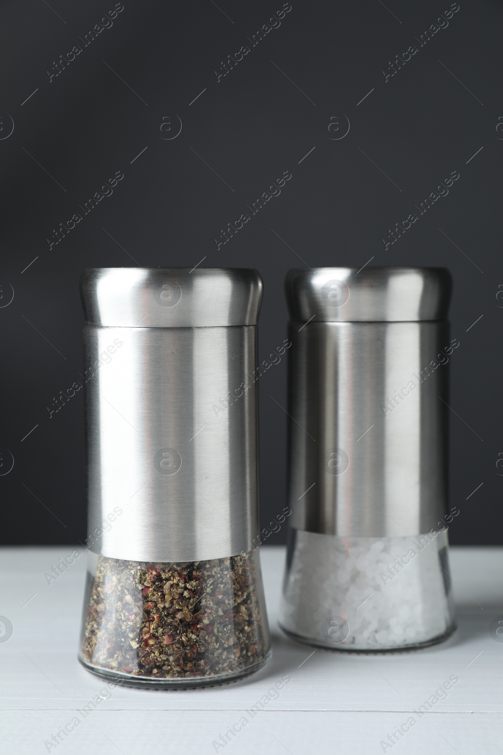 Photo of Salt and pepper shakers on white table, closeup