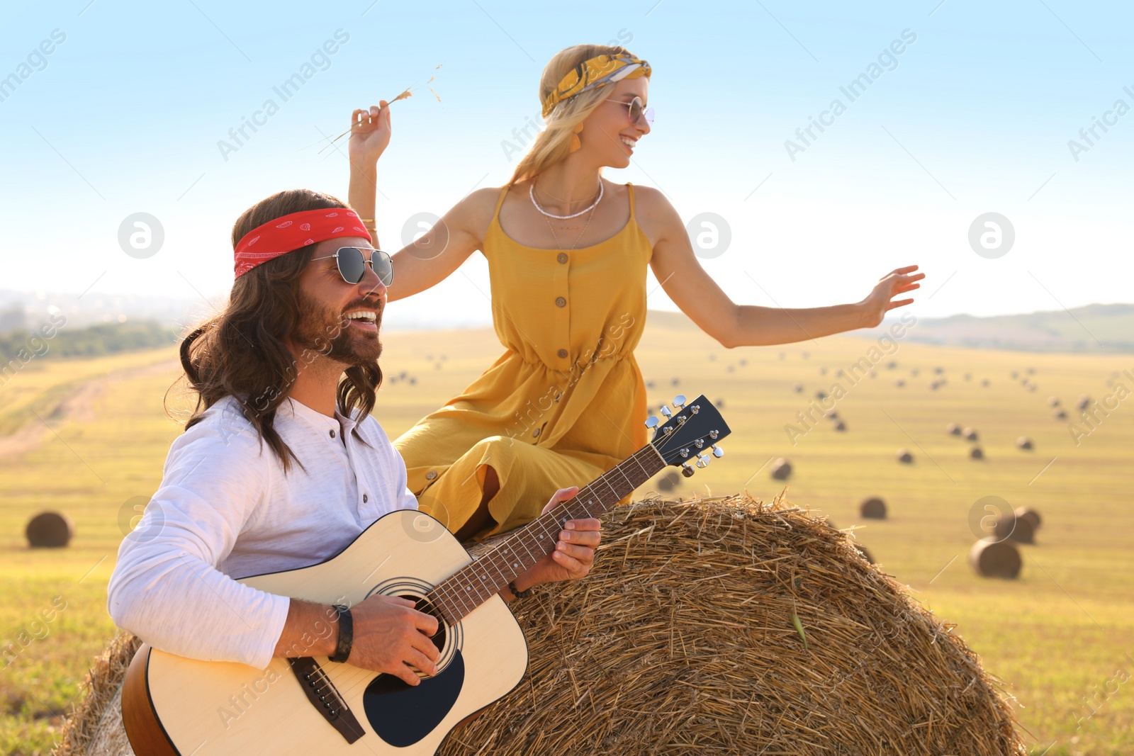 Photo of Beautiful hippie woman listening to her friend playing guitar in field