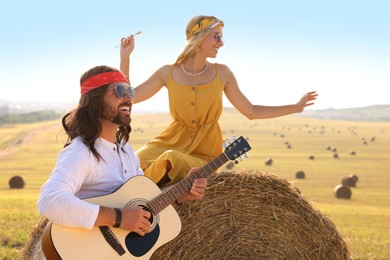 Beautiful hippie woman listening to her friend playing guitar in field