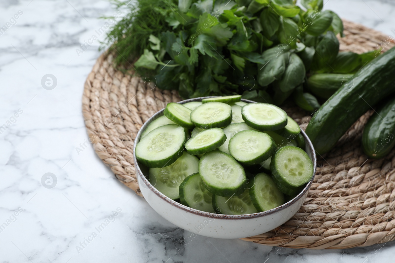 Photo of Fresh ripe cucumbers and greens on white marble table