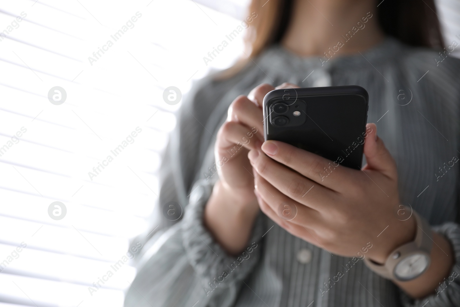 Photo of MYKOLAIV, UKRAINE - MARCH 16, 2020: Woman holding iPhone 11 Black indoors, closeup