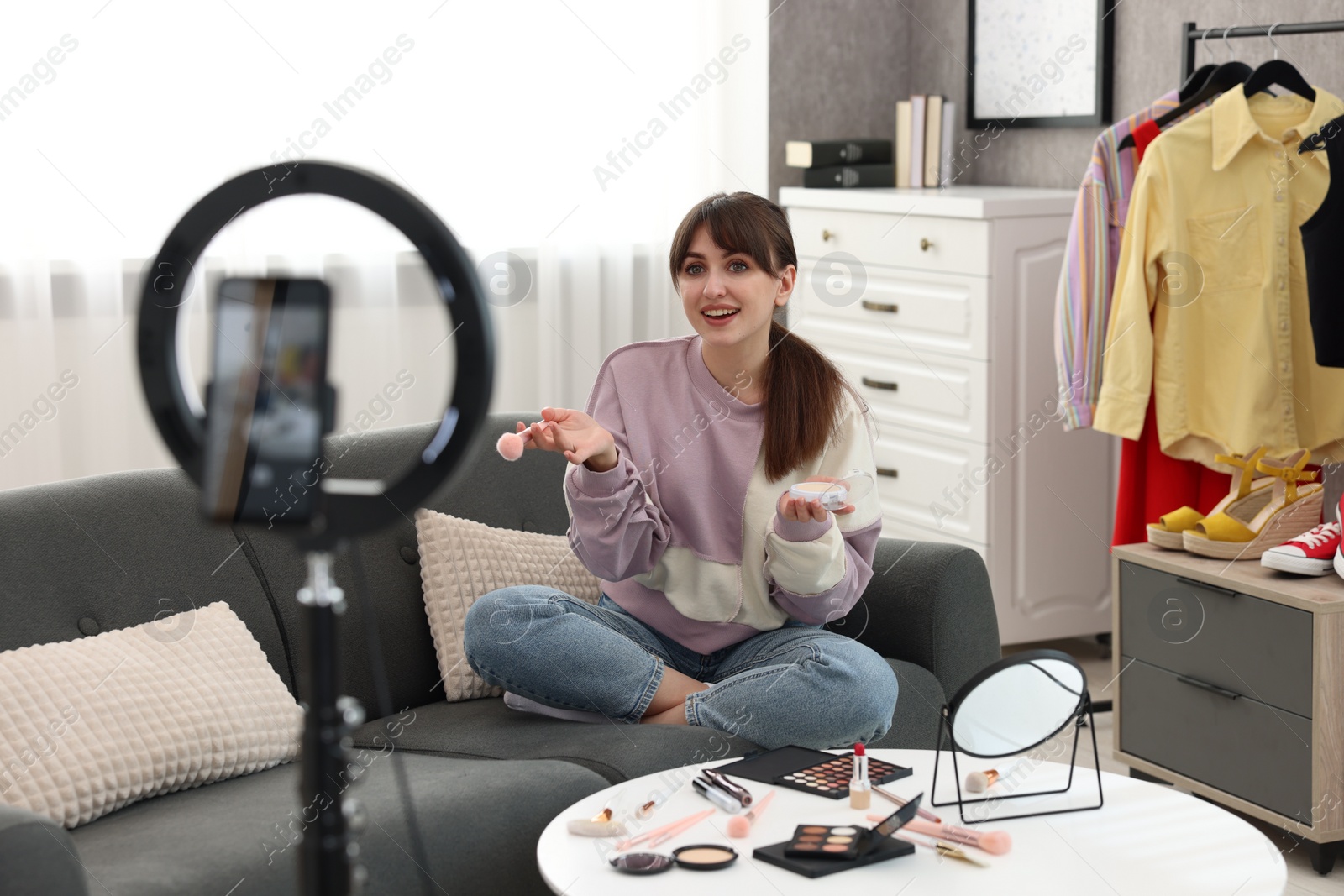 Photo of Smiling beauty blogger recording makeup tutorial at home