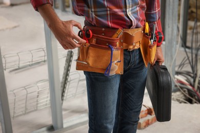 Professional builder with tool belt indoors, closeup