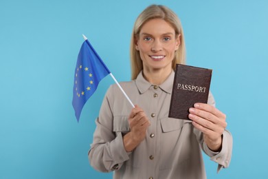 Immigration. Happy woman with passport and flag of European Union on light blue background, selective focus