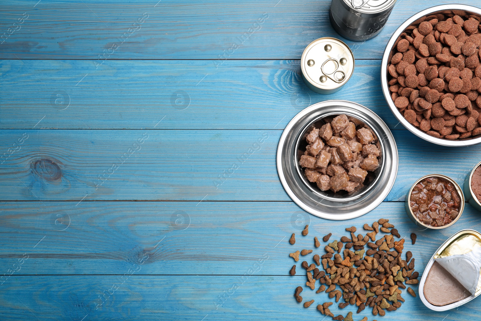 Photo of Wet and dry pet food on light blue wooden table, flat lay. Space for text