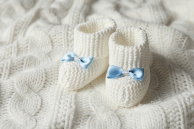 Handmade baby booties on soft knitted plaid