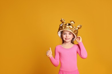 Photo of Cute girl in inflatable crown on yellow background, space for text. Little princess
