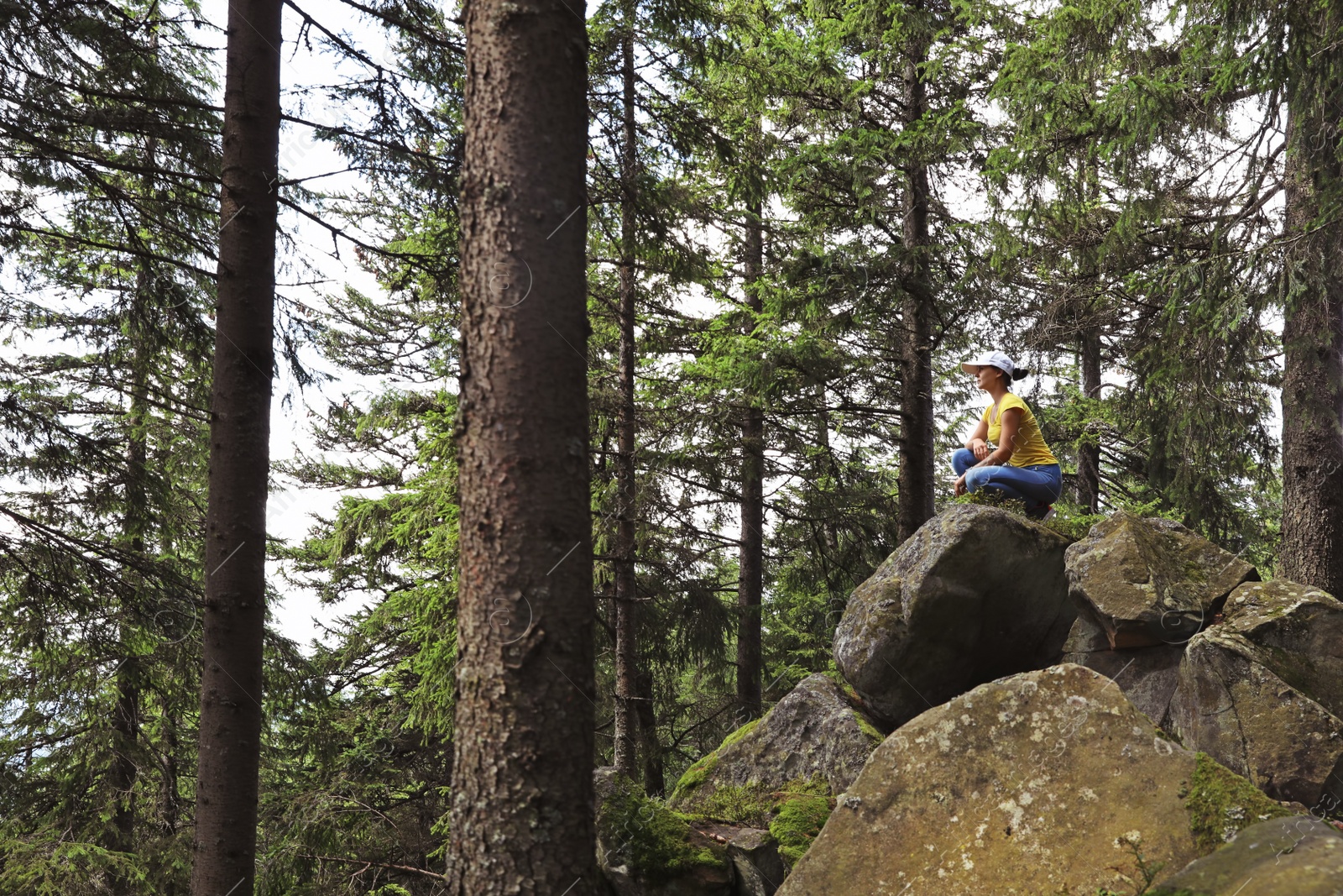 Photo of Young woman resting on rocks in beautiful forest