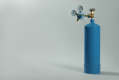 Photo of Medical oxygen tank on light grey background. Space for text