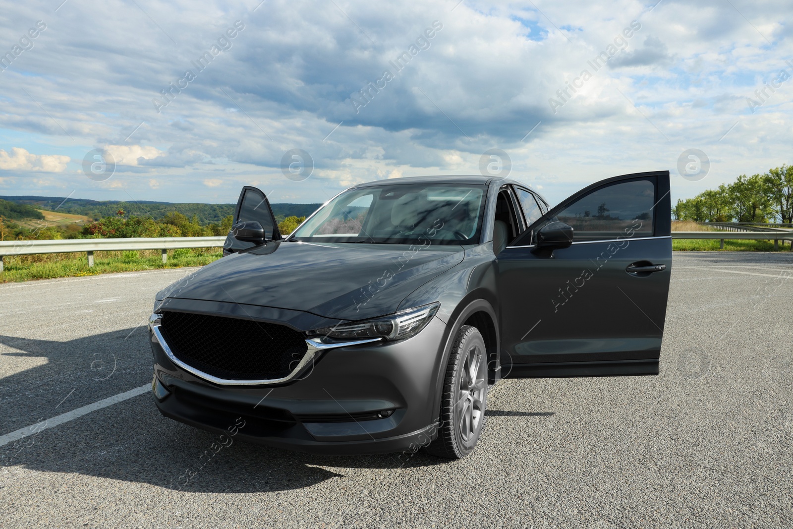 Photo of New black modern car with open doors on asphalt road