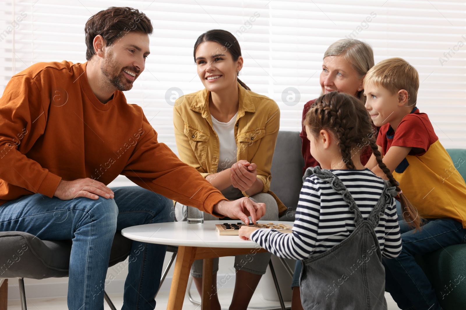 Photo of Family playing checkers at coffee table in room