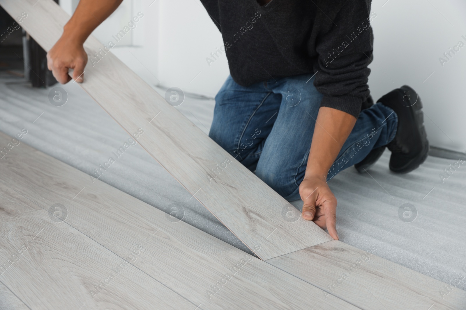 Photo of Worker installing new laminate flooring in room, closeup