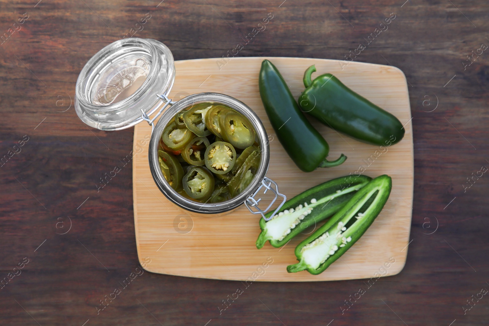 Photo of Fresh and pickled green jalapeno peppers on wooden table, top view