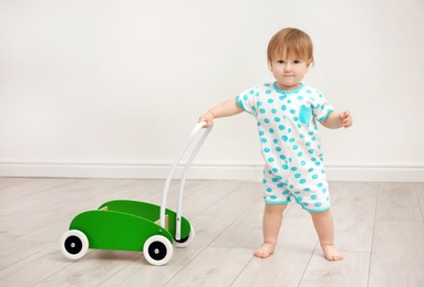 Photo of Cute baby playing with toy walker, indoors