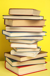 Stack of different hardcover books on yellow background