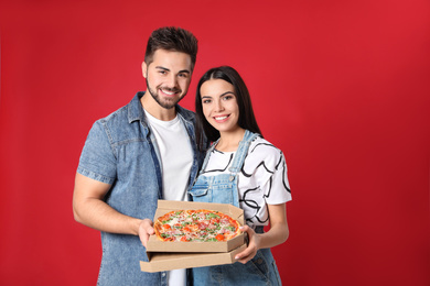 Photo of Happy young couple with pizza on red background