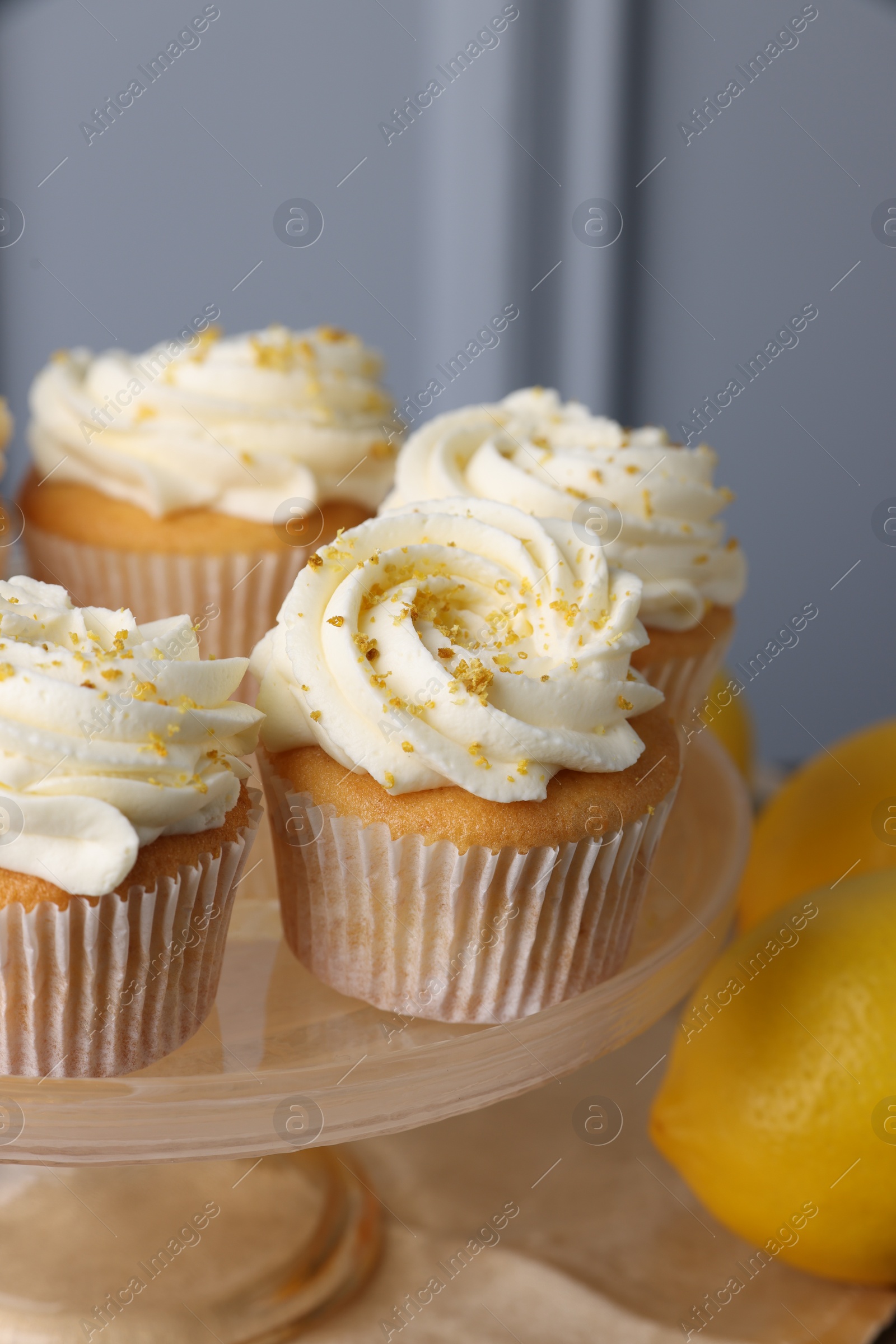 Photo of Delicious lemon cupcakes with white cream on table, closeup