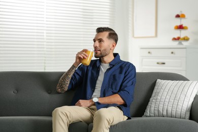 Photo of Handsome man with delicious smoothie on sofa at home