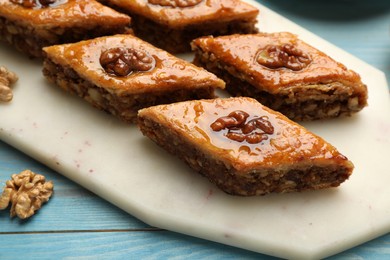 Photo of Delicious sweet baklava with walnuts on turquoise wooden table, closeup