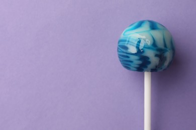 Photo of Tasty lollipop on violet background, top view. Space for text