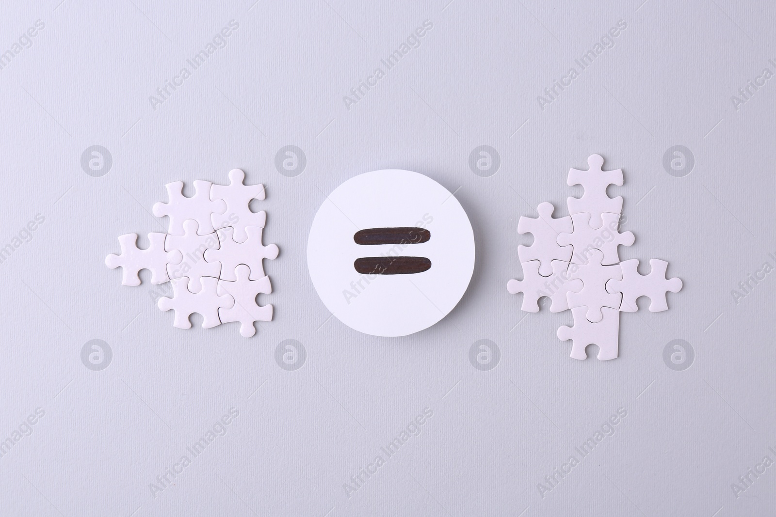 Photo of Puzzle pieces and equals sign on light background, flat lay