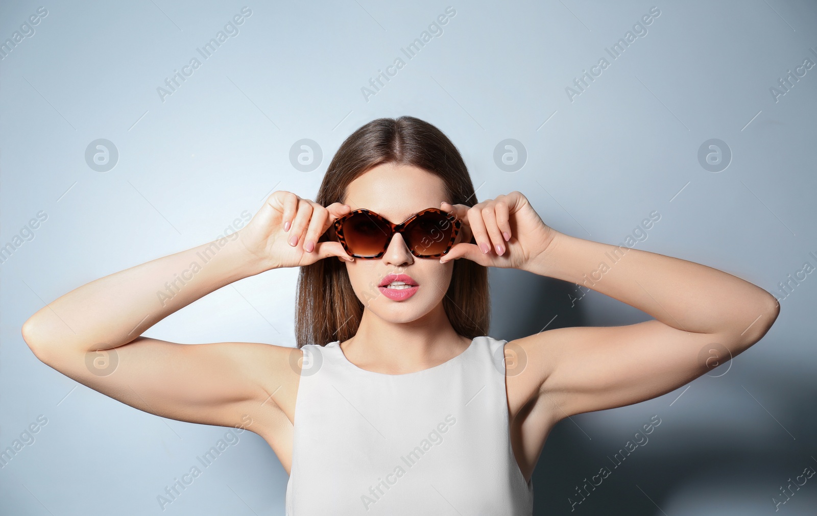 Photo of Young woman wearing stylish sunglasses on light grey background