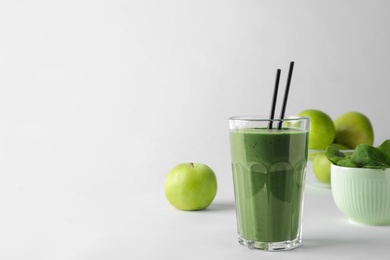 Glass of spirulina smoothie, apples and spinach on white background. Space for text