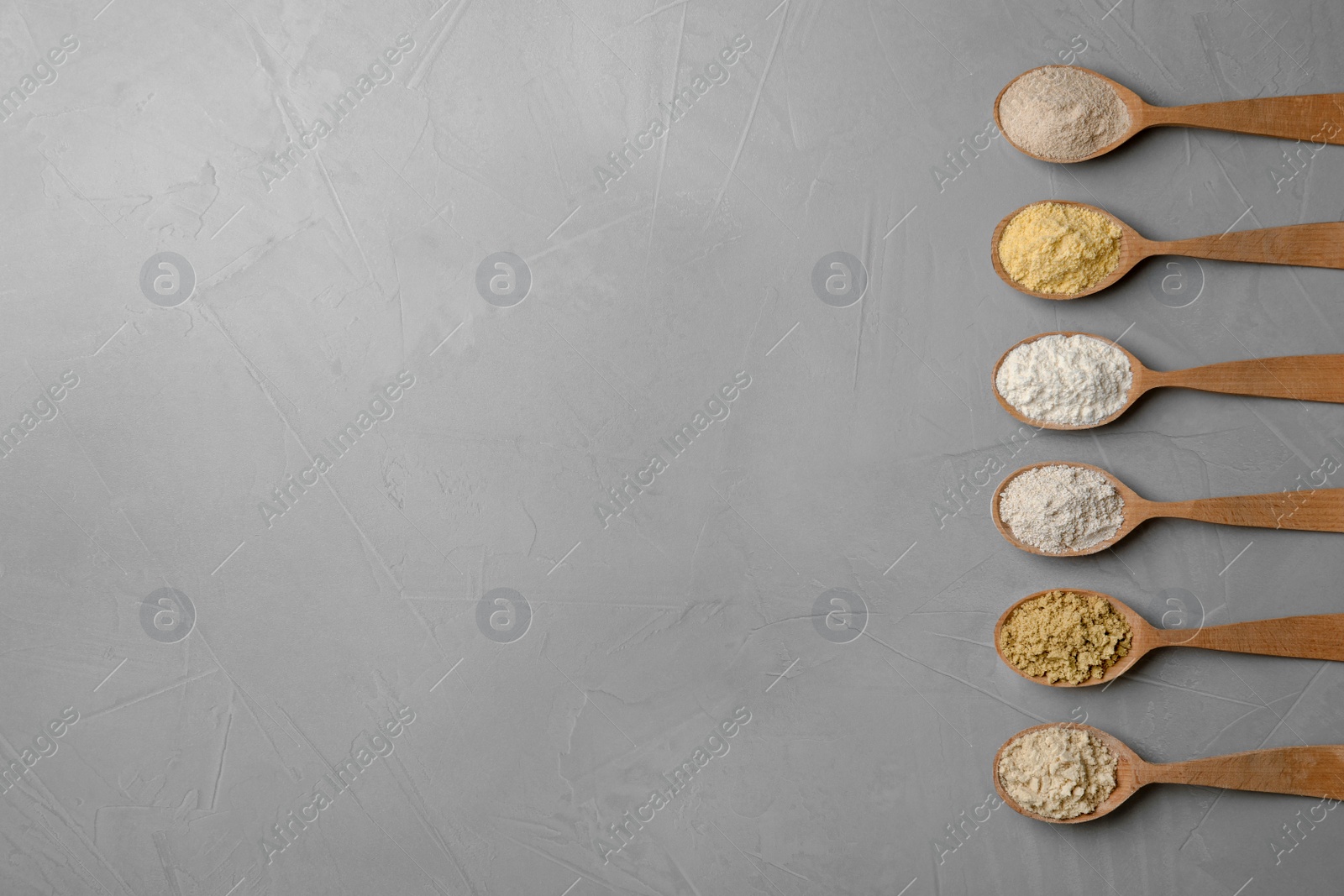 Photo of Spoons with different types of flour on gray background