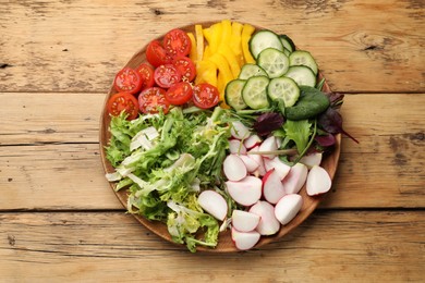 Photo of Vegetarian diet. Plate with tasty vegetables on wooden table, top view