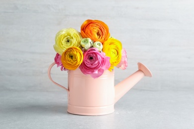 Photo of Beautiful ranunculus flowers in watering can on table